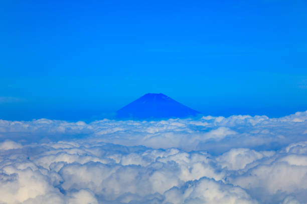 Aerial view of Fuji mountain in Japan peaking above the clouds in the distance.