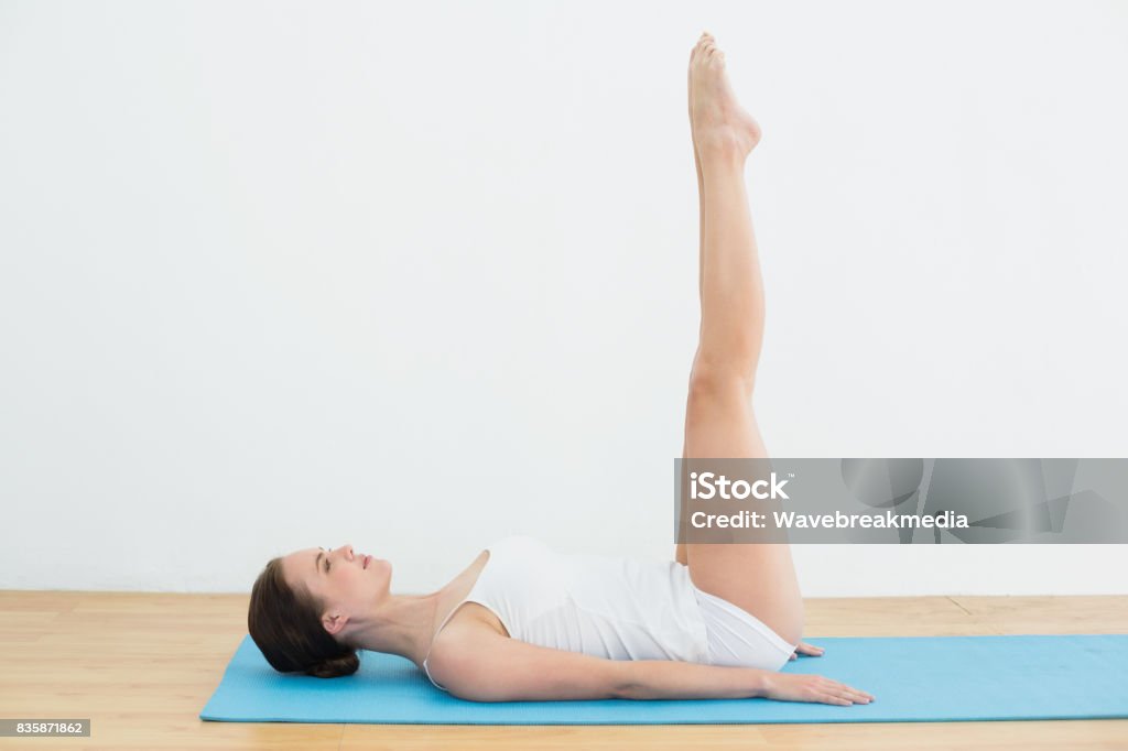 Side view of a woman stretching legs on exercise mat Full length side view of a young woman stretching legs on exercise mat 20-29 Years Stock Photo