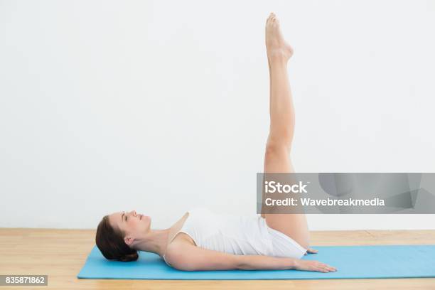 Side View Of A Woman Stretching Legs On Exercise Mat Stock Photo - Download Image Now