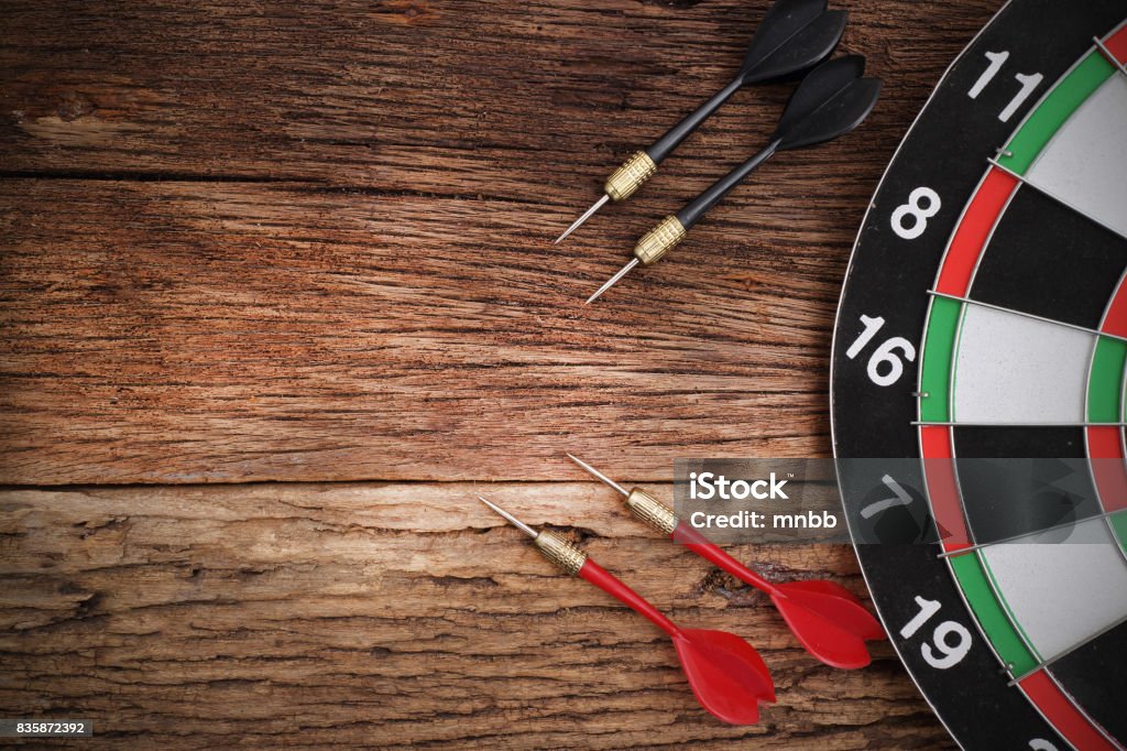 Red dart arrow hitting in the target center of dartboard Darts Stock Photo