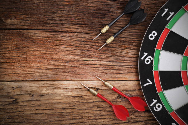 red dart arrow hitting in the target center of dartboard - dart imagens e fotografias de stock