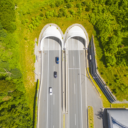 Aerial view of highway tunnel in mountains. Traffic on the road. Transportation from above. Industrial background.