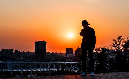 young man looks at a beautiful sunset in a big city