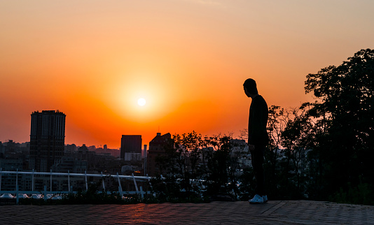 young man looks at a beautiful sunset in a big city