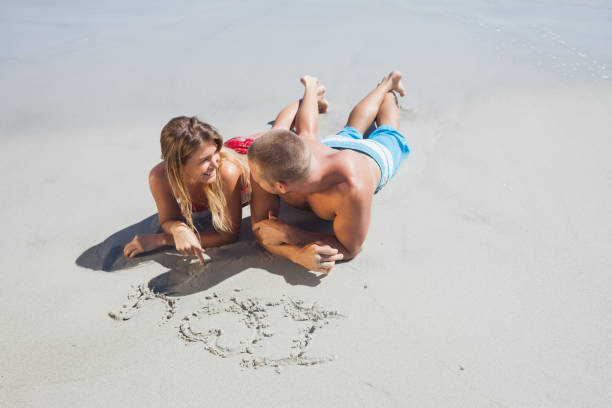 Loving couple drawing in the sand together