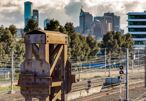 Old rusty Iron girders above a train line with the Melbourne city skyline in the background.