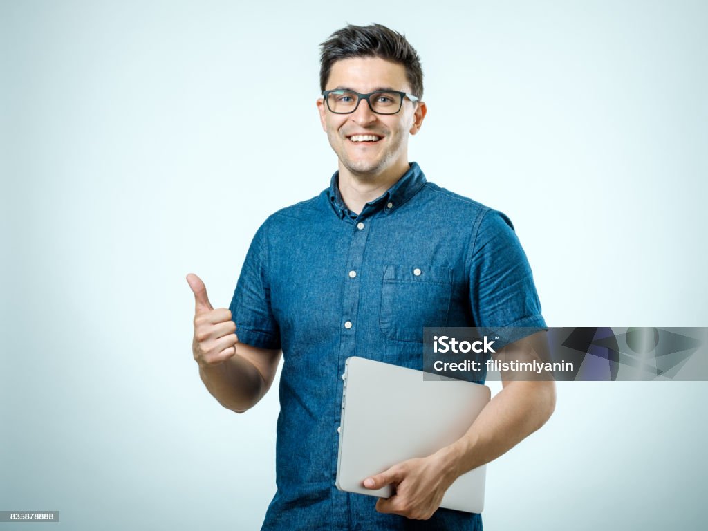 Sicher schönen jungen Mann im Hemd holding Laptop stehend vor weißem Hintergrund - Lizenzfrei Arbeiten Stock-Foto