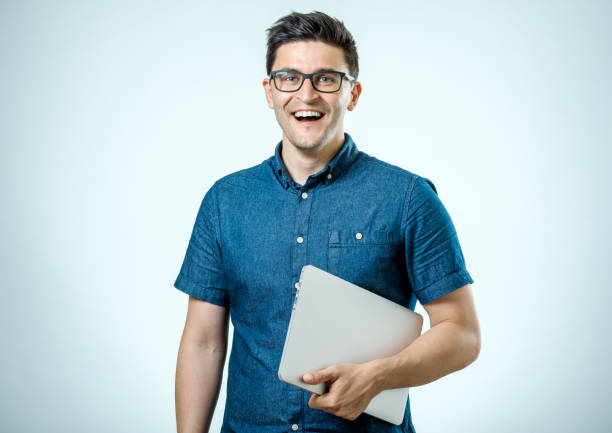 istock Confident young handsome man in shirt holding laptop while standing against white background 835878900
