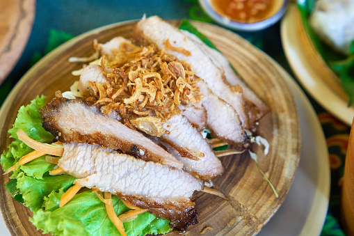 Grilled pork neck, sprinkle with shallots, and salad with vegetable salad. On a wooden dish A native of Thailand.