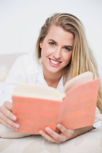 istock Smiling gorgeous model lying on cosy bed reading book 835884914