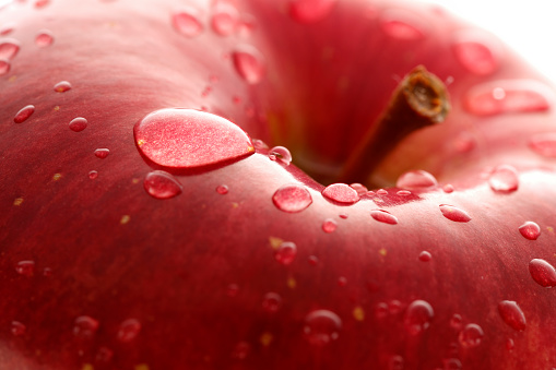 Close-up of water droplets on a fresh apple ; shot with very shallow depth of field ,