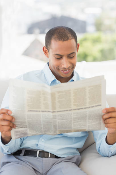 istock Smiling businessman reading newspaper on the couch 835896474