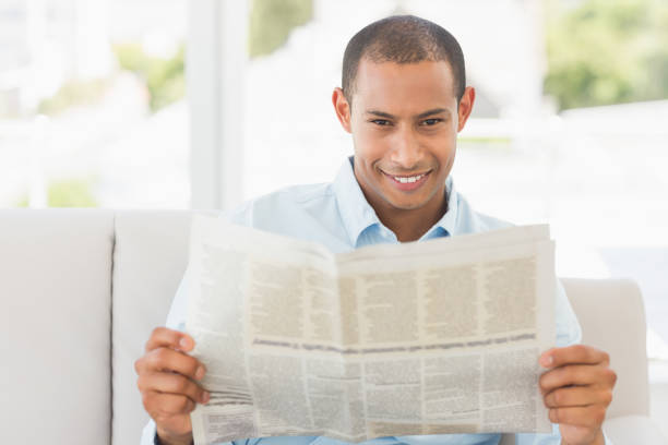istock Smiling businessman reading newspaper on the couch 835896520