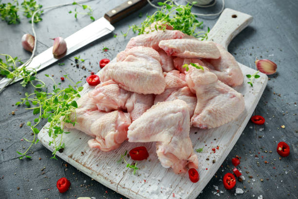 istock Fresh raw chicken wings on a white cutting board with thyme, chilli, salt, pepper, garlic 835903290