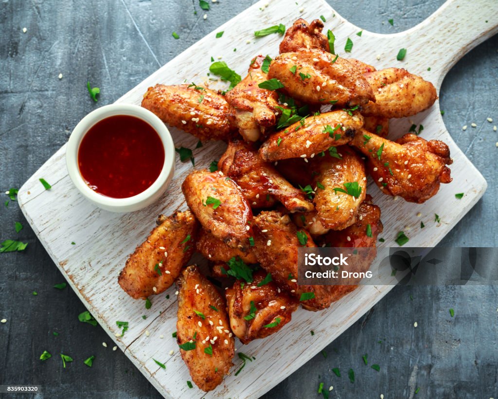Baked chicken wings with sesame seeds and sweet chili sauce on white wooden board. Baked chicken wings with sesame seeds and sweet chili sauce on white wooden board Chicken Wing Stock Photo