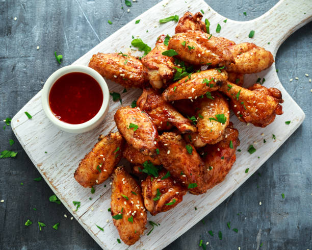 Baked chicken wings with sesame seeds and sweet chili sauce on white wooden board. Baked chicken wings with sesame seeds and sweet chili sauce on white wooden board sauce photos stock pictures, royalty-free photos & images