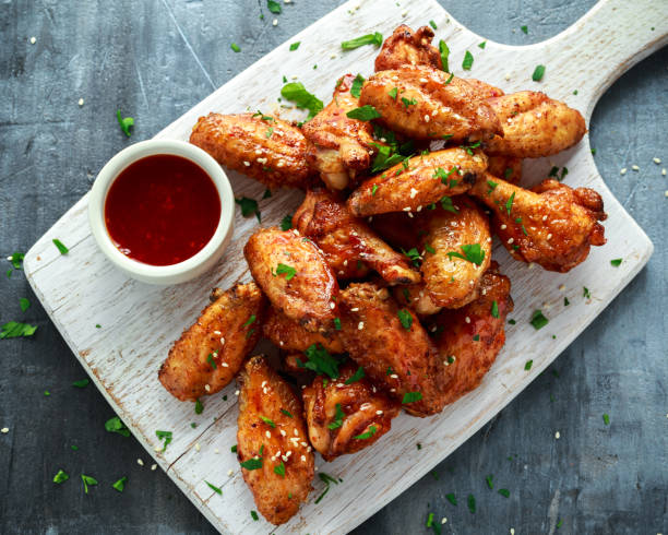 Baked chicken wings with sesame seeds and sweet chili sauce on white wooden board. Baked chicken wings with sesame seeds and sweet chili sauce on white wooden board nugget photos stock pictures, royalty-free photos & images