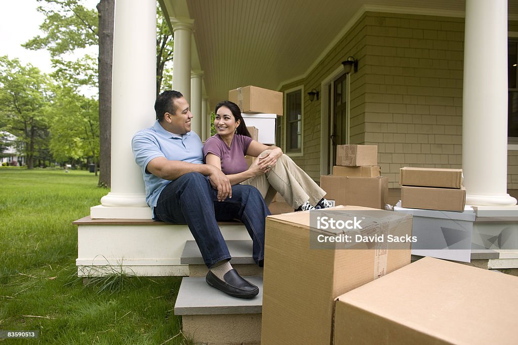 Happy couple with boxes, talking on porch  Home Ownership Stock Photo