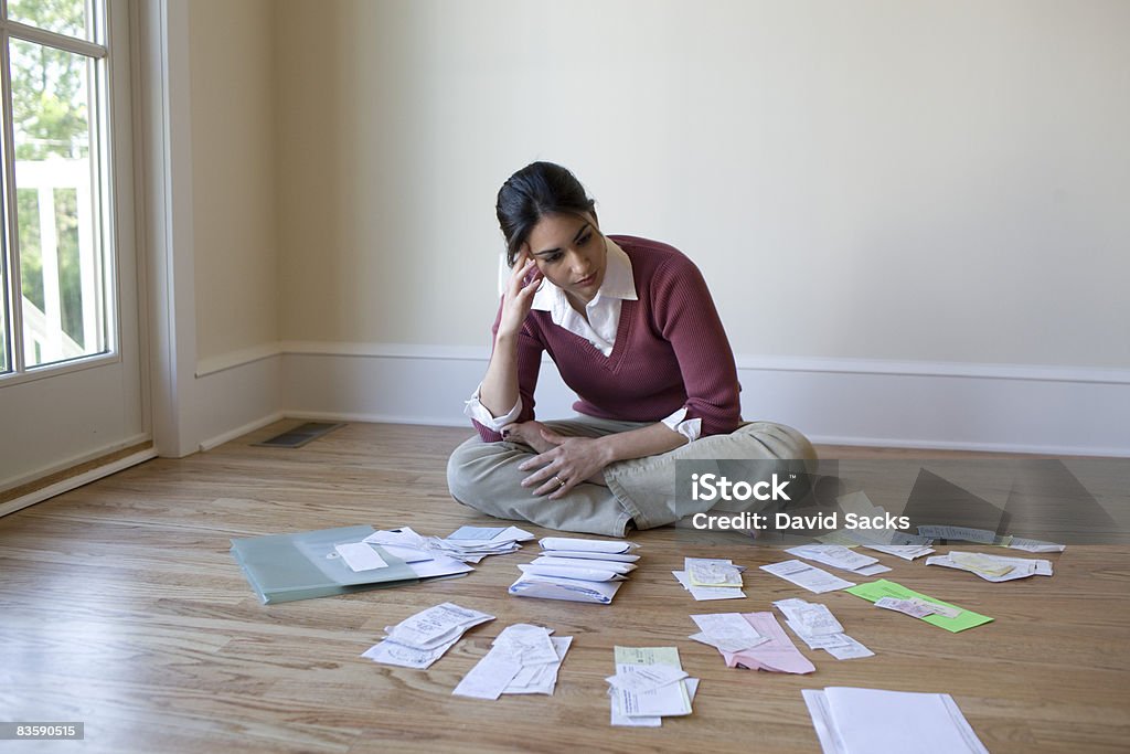 Woman looking at bills and receipts on floor  Debt Stock Photo