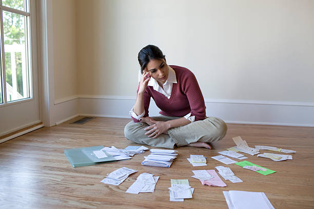 Woman looking at bills and receipts on floor  bills and taxes stock pictures, royalty-free photos & images