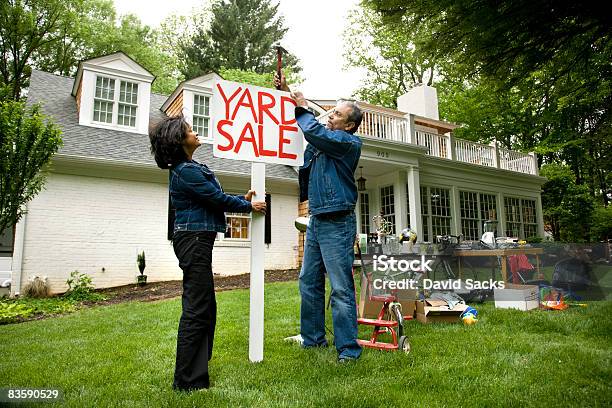Mature Couple Putting Up Sign For Yard Sale Stock Photo - Download Image Now - People, 50-54 Years, Car Trunk Sale