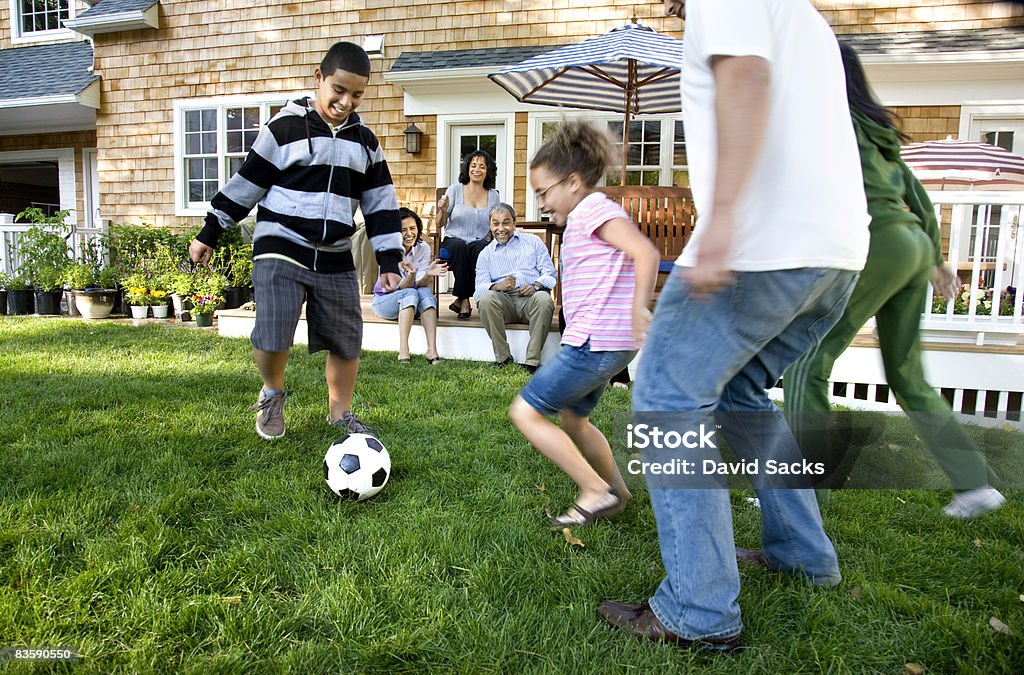 Familia jugando al fútbol en la zona suburbana de jardín - Foto de stock de Familia libre de derechos