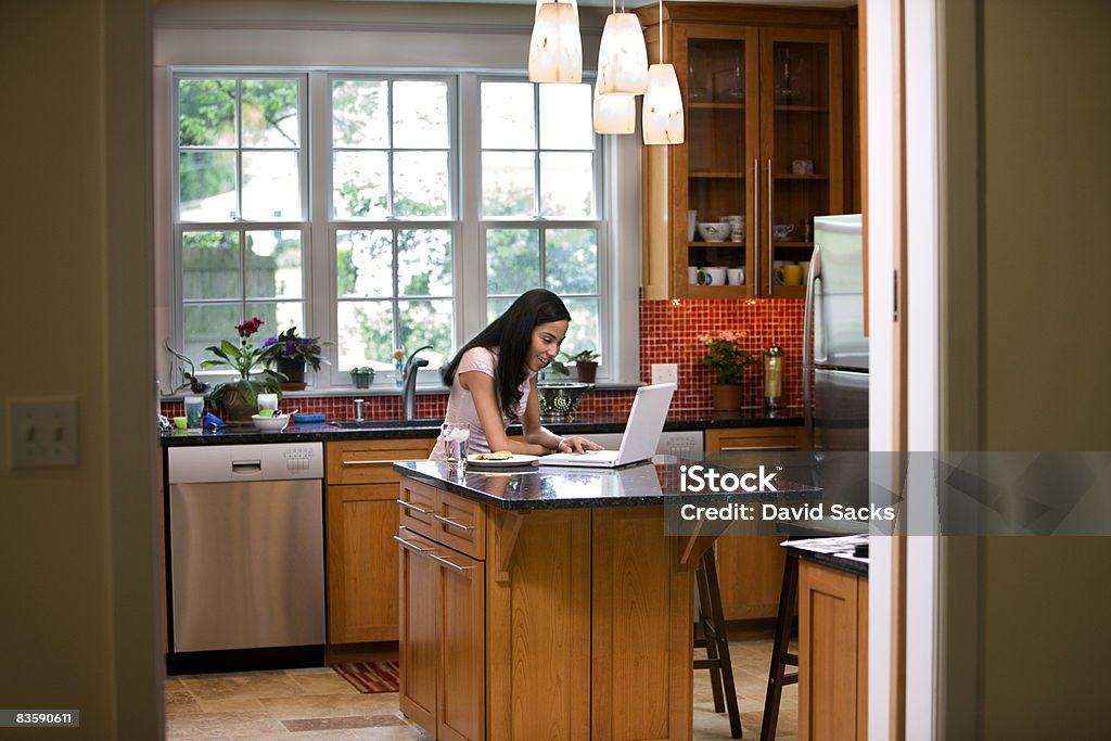 Woman in kitchen on laptop  Chandelier Stock Photo