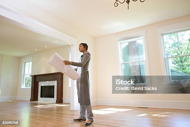 Woman Looking At Blueprints In Newly Built Home Stock Photo - Download Image Now - Examining, Real Estate, Real Estate Agent