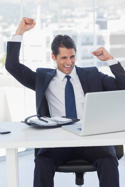 istock Businessman cheering and looking at his laptop 835909864