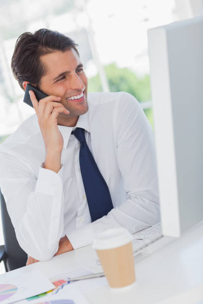 istock Smiling businessman on the phone looking at his computer 835909972
