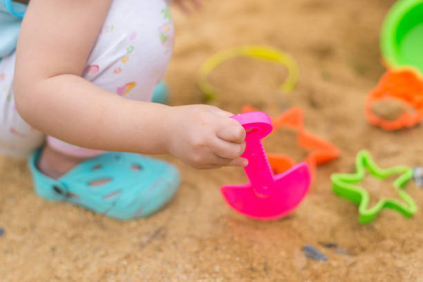 istock Kid hand playing with plastic toy in sand box 835910430