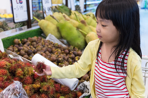Asian Little Chinese Girl choosing fruits in supermarket