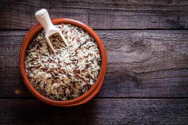 marrón recipiente llenado de arroz mezclado tiro desde arriba en la mesa de madera rústica - dishware brown rice rice variation fotografías e imágenes de stock