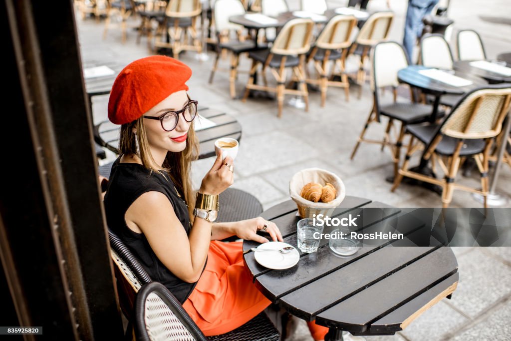 Woman having a french breakfast at the cafe Young stylish woman in red beret having a french breakfast with coffee and croissant sitting oudoors at the cafe terrace Paris - France Stock Photo