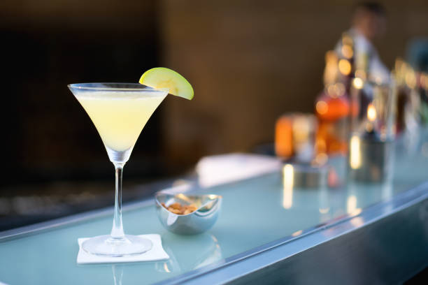 martini manzana cóctel alcohólico tirado en el bar con desenfoque de bartender en fondo. - apple martini fotografías e imágenes de stock