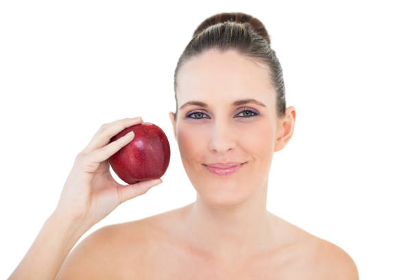 istock Smiling woman holding red apple looking at camera 835940662