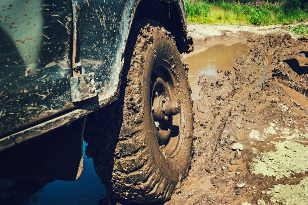 Off road car stuck in deep mud with flat tire.