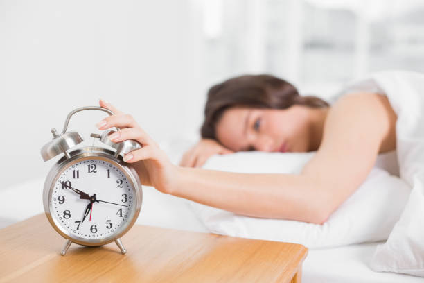 istock Blurred woman in bed extending hand to alarm clock 835949422