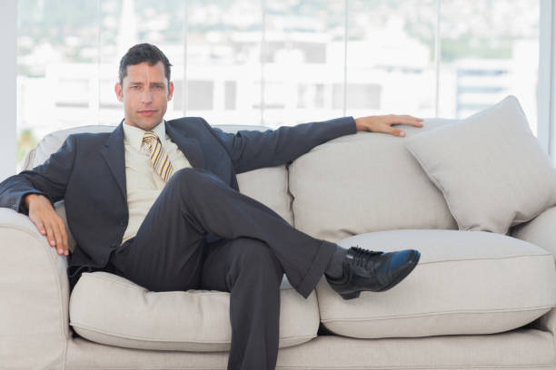 istock Serious businessman in suit posing sitting on sofa 835961300