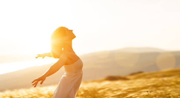 istock Happy woman standing with her back on sunset in nature iwith open hands 835976522
