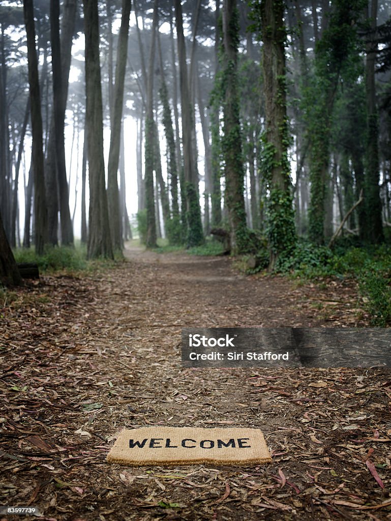 Welcome mat on ground at entrance to forest Doormat Stock Photo