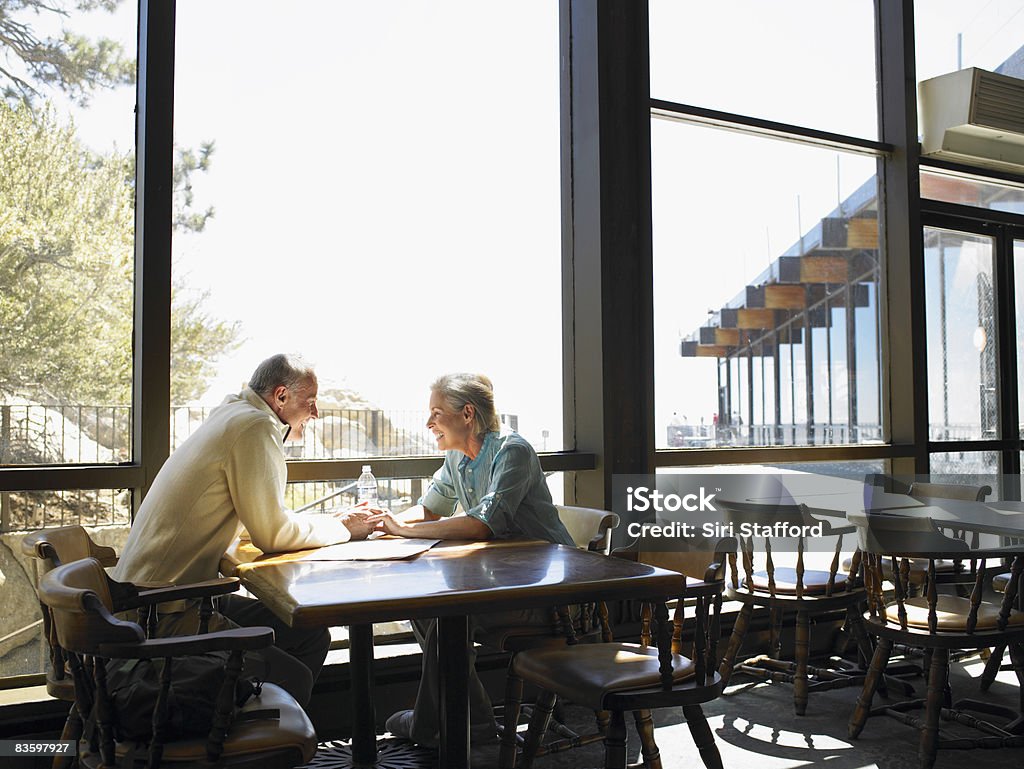 Mature Couple holding hands in restaurant Couple together in restaurant at top of tramway in the San Jacinto Mountains. Restaurant Stock Photo