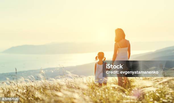 Happy Family In Summer Outdoors Mother And Child Daughter Stand With Their Backs On Sunset Stock Photo - Download Image Now