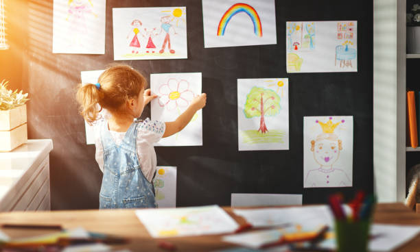 istock child girl hanging her drawings on wall 835987402