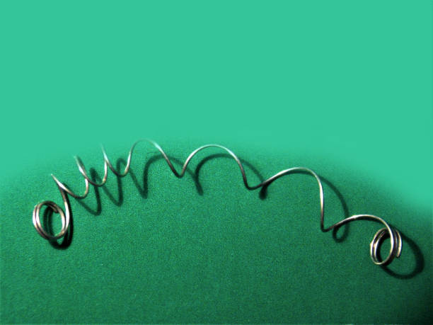 Unsprung - Close-Up Image of Silver Coiled Metal Spring Pulled and Stretched Disfigured, Non-functioning, and now Unusable Small Coiled Metal Spring photographed on an Iridescent Neon Green Colored Background. broken spring stock pictures, royalty-free photos & images