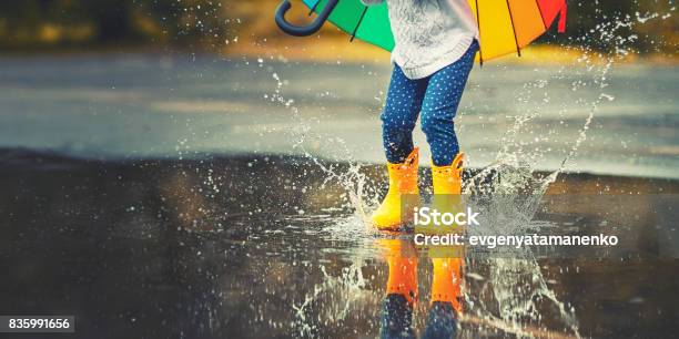 Feet Of Child In Yellow Rubber Boots Jumping Over Puddle In Rain Stock Photo - Download Image Now