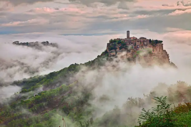 Civita di Bagnoregio, Viterbo, Lazio, Italy: picturesque landscape at dawn of the ancient village shrouded in fog on the steep tuff hill