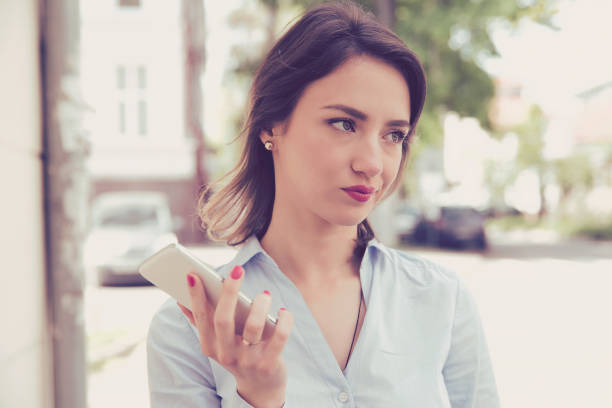 frustré de femme triste ennuyée avec téléphone portable debout à l’extérieur dans la rue avec un fond urbain - irritants photos et images de collection