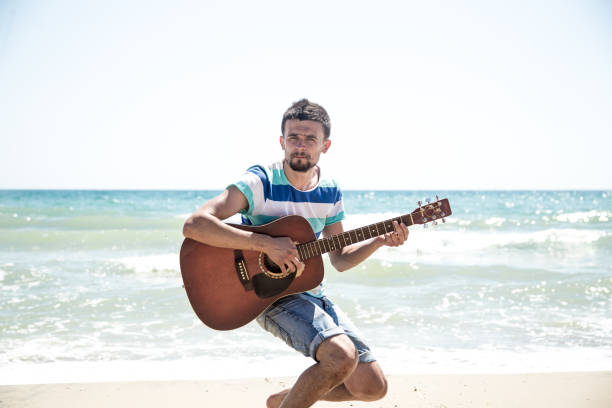 istock young man with acoustic guitar on the beach 836004804