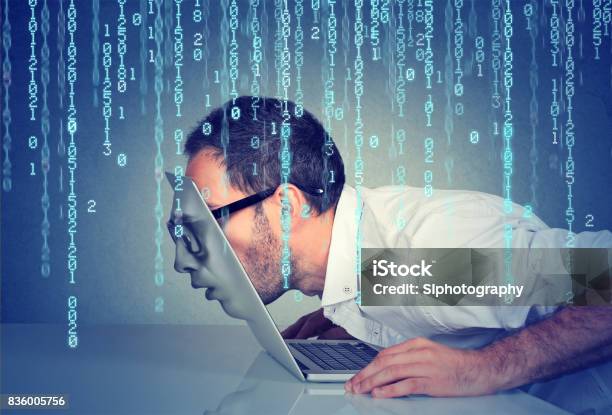Side Profile Of A Young Business Man With His Face Passing Through The Screen Of A Laptop On Binary Code Background Stock Photo - Download Image Now